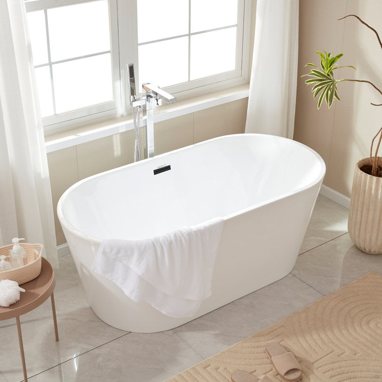 Compact white freestanding tub with a deck faucet in a bright small bathroom