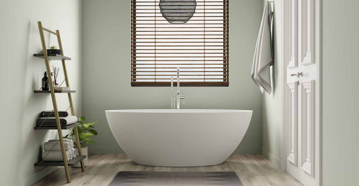 White freestanding bathtub in a sage green bathroom with a wooden ladder shelf