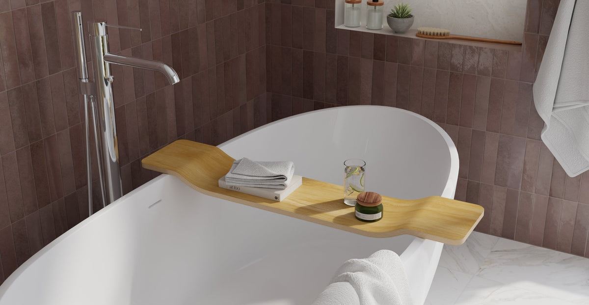 Natural oak bath caddy resting across a white freestanding tub