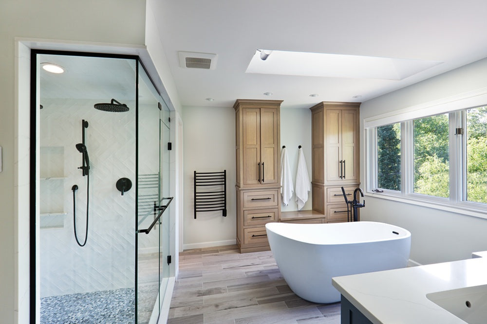 Remodeled bathroom with a glass shower, freestanding tub and wood cabinetry