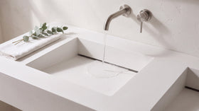 Water running down a white ramp basin into the hidden slot drain at the back