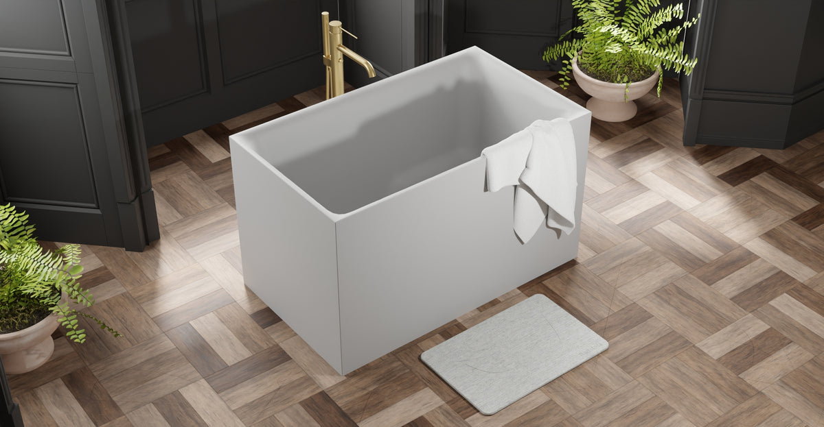Badeloft BW-06-S freestanding bathtub in matte grey seen from above on a herringbone wood floor with paneled walls