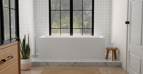 Badeloft BW-07 freestanding bathtub in matte white on a raised marble platform with square wall tile and paned windows