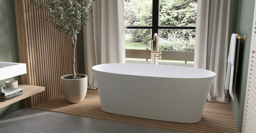 Badeloft BW-12 freestanding bathtub in white on a wood-slat floor by linen curtains and a potted olive tree
