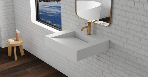 Badeloft WT-04-E wall-mounted sink in matte white on a brick-pattern tile wall below a window, with a wood stool